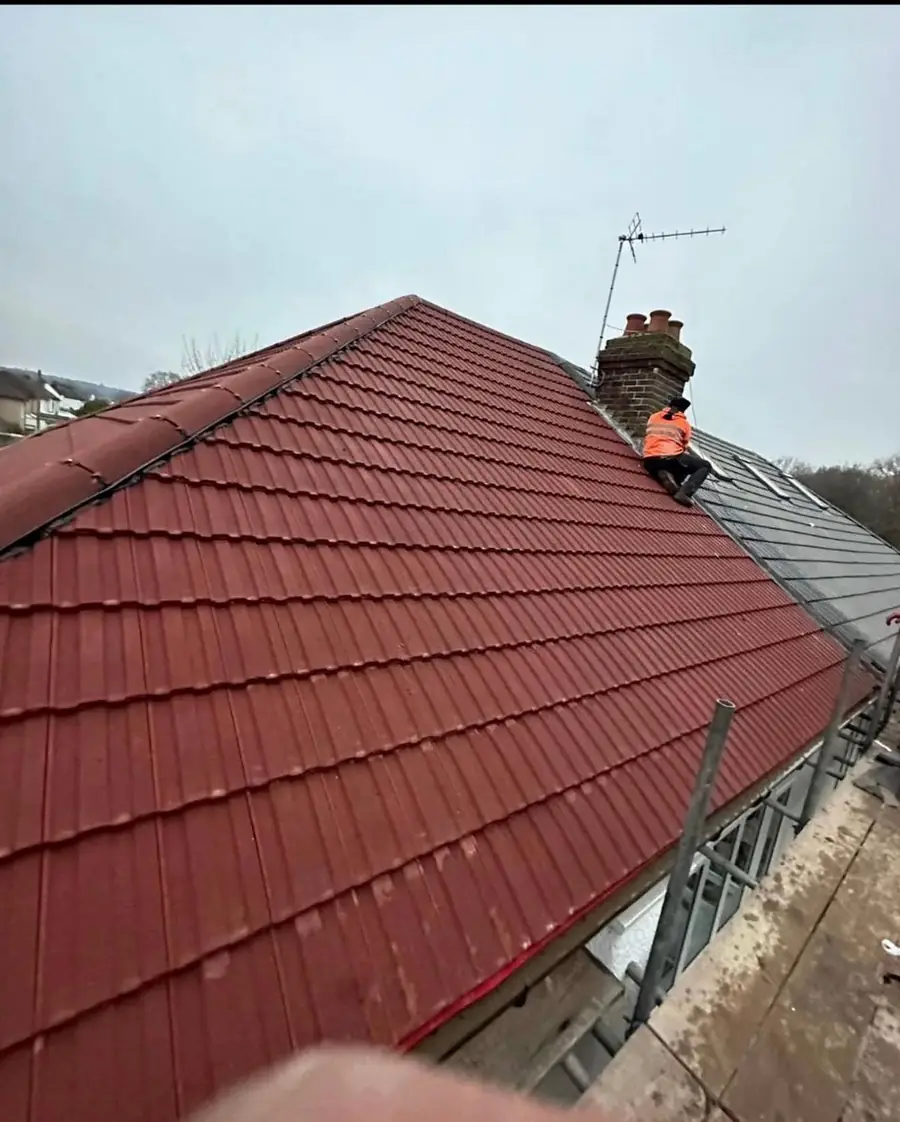 Roofer laying red interlocking tiles up a pitched roof